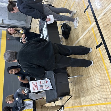 Two students administering grip strength tests to fair attendees.
