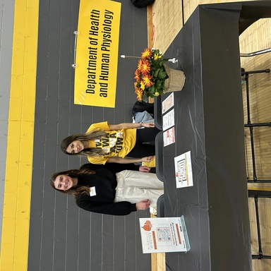Two students smiling and standing at a table representing the Health and Human Physiology department